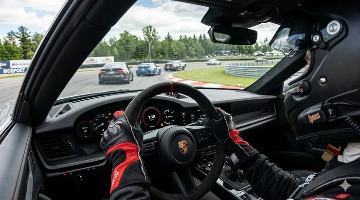 A driver wearing professional track day gloves while racing at Canadian Tire Motorsport Park (Mosport) in a high-performance vehicle.