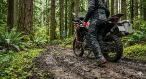 An illustration of a female motorcyclist navigating a muddy, wet dual-sport trail in British Columbia, emphasizing the deep luggage-tread sole of her women's ADV boots small sizes.
