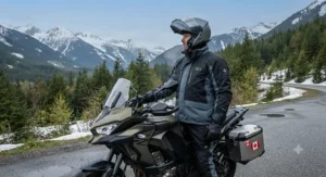 An adventure rider navigating a muddy prairie gravel road wearing a rugged waterproof rain jacket and pants set built for extreme weather protection.