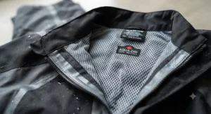 A close-up illustration of a breathable motorcycle rain suit interior showing moisture-wicking mesh lining.