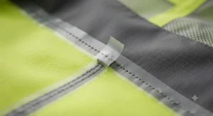 Close-up illustration of sealed waterproof seams on a hi-vis rain jacket designed for motorcycle commuting.