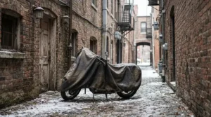 A motorcycle cover for outdoor winter storage fitted tightly on a sportbike parked behind a city townhouse.