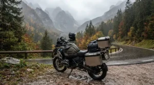 A female rider stopping her adventure bike in the Rocky Mountains wearing a black and grey women's motorcycle rain suit.