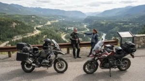 Two riders showcasing different colour and style options of a modern women's motorcycle rain suit at a scenic lookout.