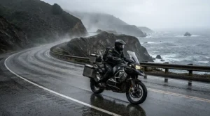 A woman wearing a high-visibility yellow women's motorcycle rain suit while riding along a wet Pacific Northwest coastal highway in British Columbia.